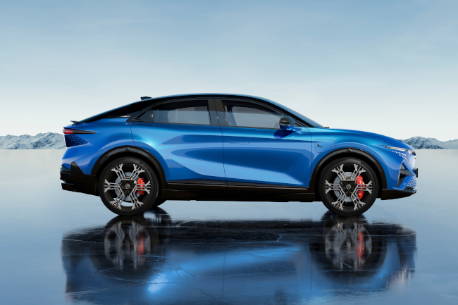 Seitliche Ansicht eines blauen sportlichen Autos auf einem reflektierenden Boden mit Bergen im Hintergrund.